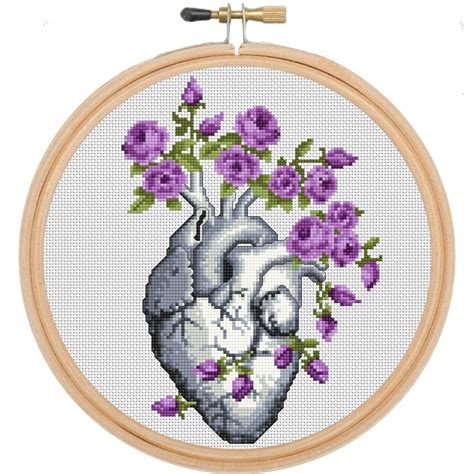 A Cross Stitch Heart With Purple Flowers In It