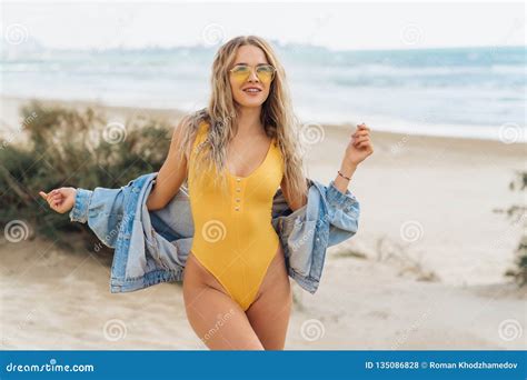 Blonde Girl In A Yellow Swimsuit And Sunglasses Posing On The Beach Beautiful Model With