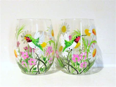 Two Hand Painted Wine Glasses Sitting Next To Each Other On A White