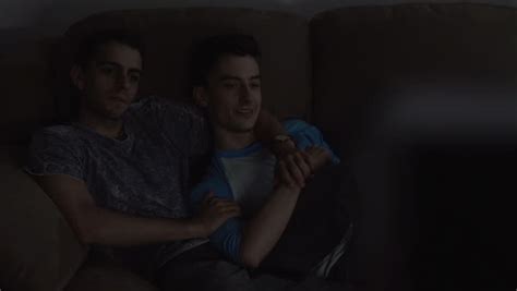 A Mid Shot Of Two Caucasian Gay Men Watching A Scary Movie On Television They Jump And Hold On