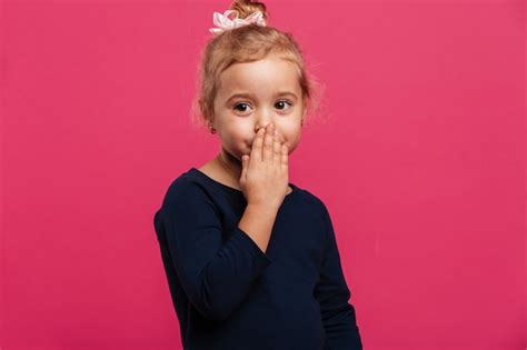 Jolie Jeune Fille Blonde Couvrant Sa Bouche Et Regardant De Côté Sur Le Mur Rose Photo Gratuite