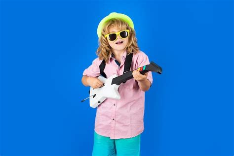 Un niño lindo canta y toca la guitarra eléctrica con emociones