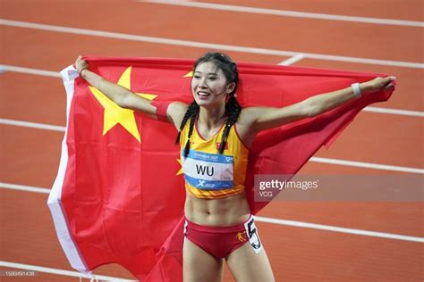 a woman holding a china flag on top of a track