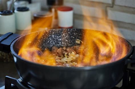 Beef Meat Fried With Onions In Frying Pan Flambe On Gas Stove Stock