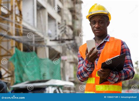 Young Black African Man Construction Worker Holding Clipboard An Stock