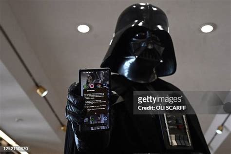 A Cosplayer Dressed As The Star Wars Character Darth Vader Holds A