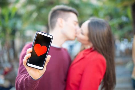 Casal Se Beijando Enquanto Mostra Um Smartphone Formato De Cora O