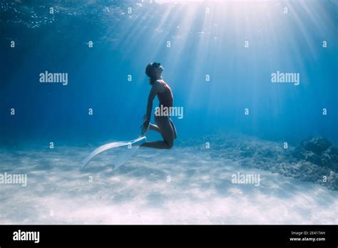 Woman Freediver In Red Swimsuit With White Fins Posing Underwater Over