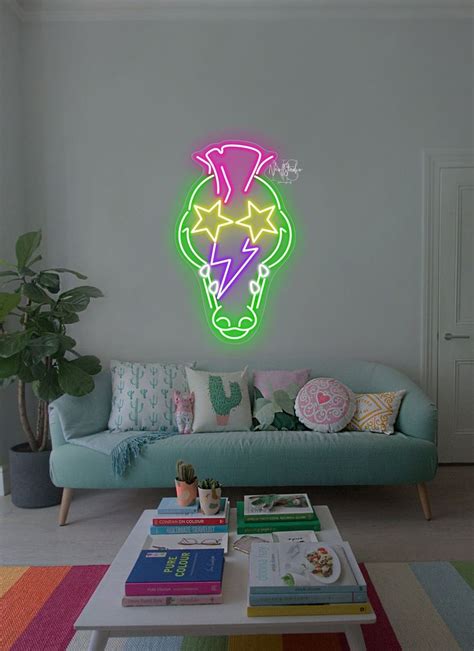 a living room with a couch, coffee table and neon sign on the wall above it