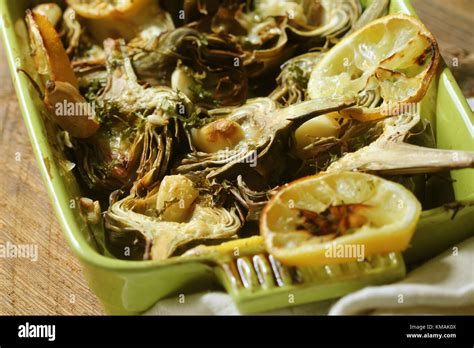 Fried Artichokes With Garlic And Lemon On Pan On Rustic Table Stock