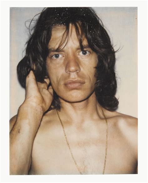 A Man With Long Hair And No Shirt Is Holding His Hand To His Ear While Looking At The Camera