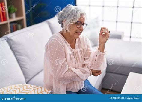 Middle Age Grey Haired Woman Sitting On Sofa Suffering For Elbow Pain