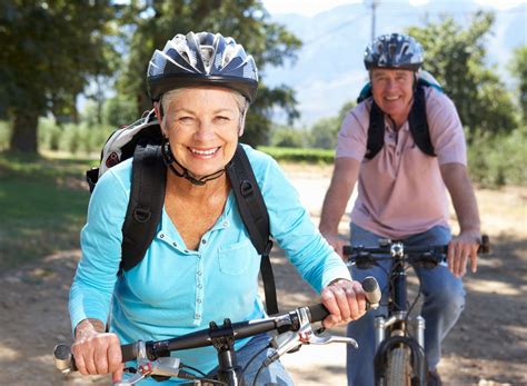 An Older Couple Riding Bikes On A Dirt Road