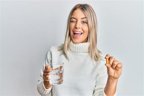 Belle Femme Blonde Tenant Une Pilule Et Un Verre D eau En Regardant La Caméra Avec Une