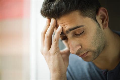 Young Man Holding His Head Out Of Headache Near Window Stock Photo