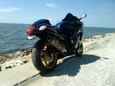 A Blue Motorcycle Parked On The Side Of A Road Next To Some Water And Rocks