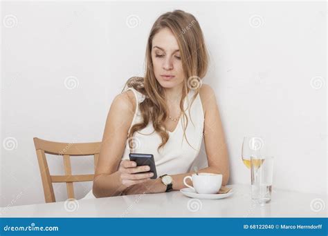 Blonde Stirring Her Coffee Looking At Mobile Phone Stock Photo Image