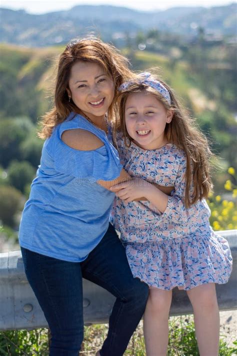 Madre E Hija De Latina Que Sonr En Y Que R En En Una Colina Delante De Las Flores Amarillas