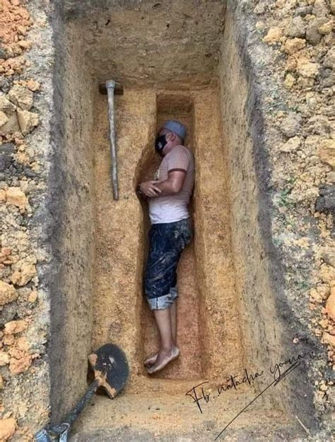 A Man Is Standing In A Hole With A Baseball Bat And Helmet On His Head