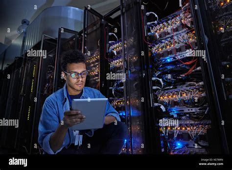 Focused Male IT Technician Using Digital Tablet In Dark Server Room