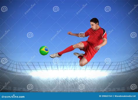 Composite Image Of Fit Football Player Jumping And Kicking Stock Photo