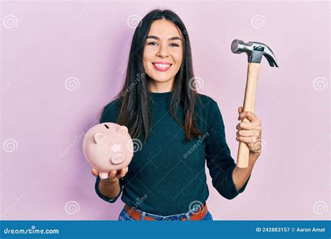 Jeune Brunette Tenant La Tirelire Et Marteau Souriant Avec Un Sourire Joyeux Et Cool Sur Le