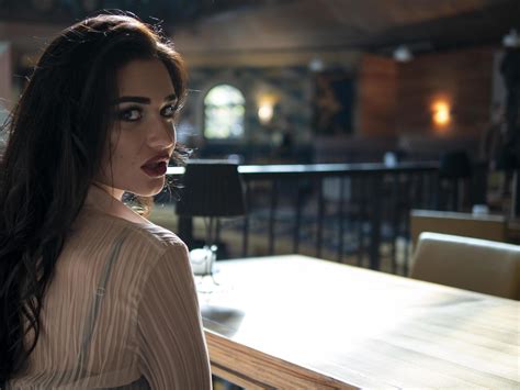 Beautiful Brunette Model Sitting On The Couch At The Table Indoors Turning Back And Looking At