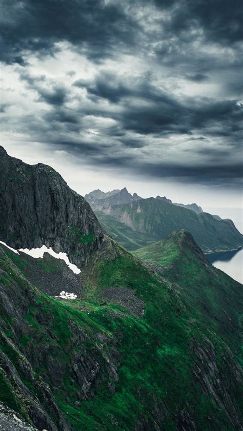 The Mountains Are Covered In Green Grass And Water Under A Cloudy Sky