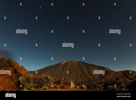 Mount Teide lit by the full moon and star trails at night in the Las Canadas del Teide National ...