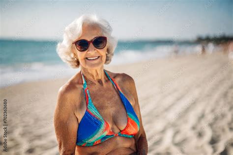 Happy Old Senior Woman In Bikini With Wrinkled Face Flabby Tanning Skin And Gray Hair Enjoys