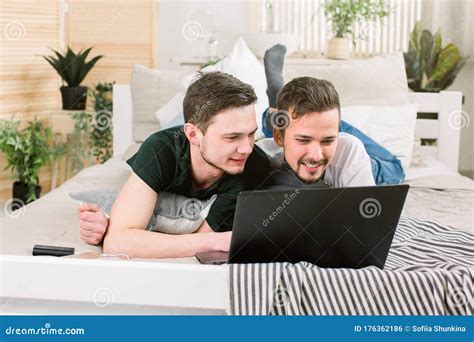Happy Gay Couple Lying On Bed With Laptop At Home Stock Photo Image Of Peaceful Couple