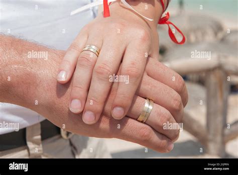 Newly Married Couple Holding Hands And Showing Off Their Wedding Rings