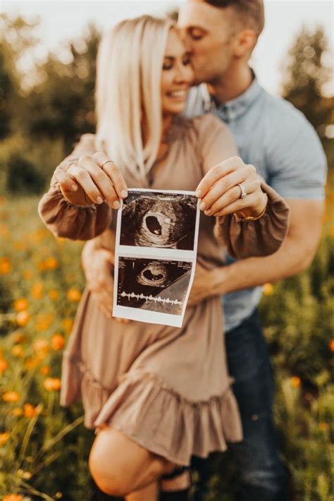 A Man And Woman Standing In A Field Holding Up A Polaroid Photo With An