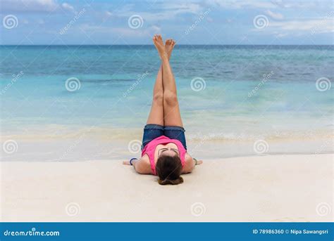 Young Women Lying On A Tropical Beach Stretching Up Slender Leg Stock