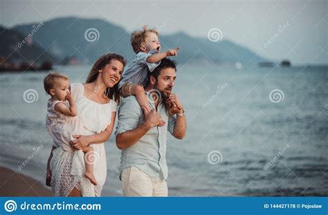 Una Familia Joven Con Dos Ni Os Del Ni O Que Se Colocan En La Playa El