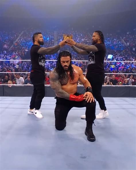 Two Men Standing On Top Of A Wrestling Ring Holding Their Hands Up In