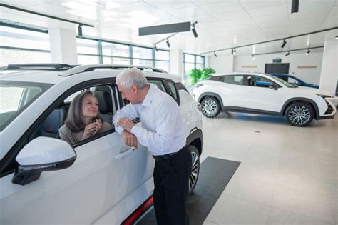Mature Caucasian Woman Sits In A New Car An Elderly Man Gives Her The Keys Stock Photo Image