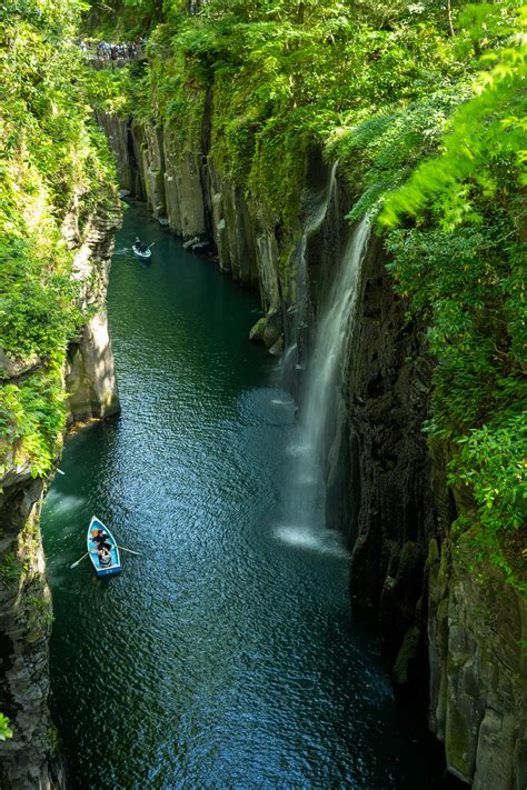 Boats navigate a scenic gorge with a waterfall. photo – Free Forest