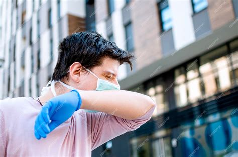 Premium Photo | Man sneezing in elbow on the street protecting from ...