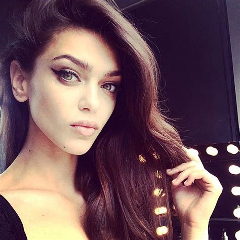 A Woman With Long Brown Hair Is Posing In Front Of A Mirror And Lights