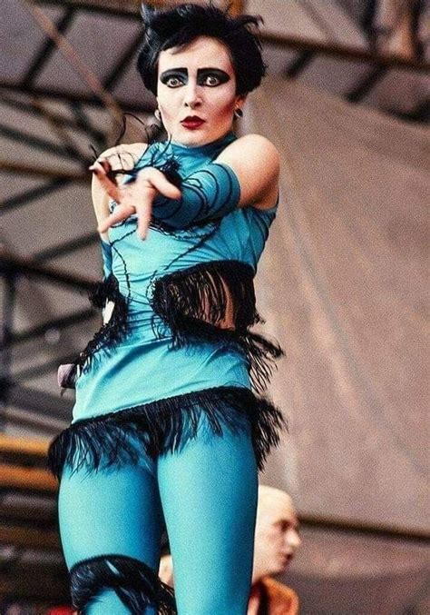 A Woman Dressed In Blue And Black With Feathers On Her Body