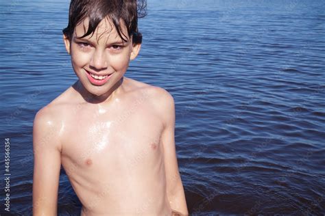 Boy With A Naked Torso And Wet Hair Posing Against A Background Of Blue Water Stock Photo