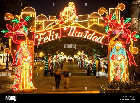 People strolling on Paseo de La Princesa under "Feliz Navidad" sign ...