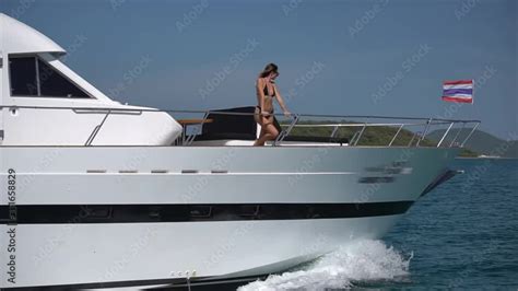Great White Yacht Sailing Along The Blue Bay Waters Slim Bikini Girl Standing On Fore Deck