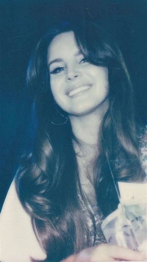 A Woman With Long Brown Hair Smiling And Holding Something In Her Hand