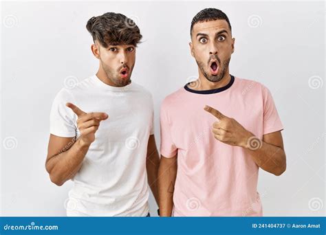 Jovem Casal Gay Parado Sobre Um Fundo Isolado Surpreso Apontando O Dedo Ao Lado Da Boca