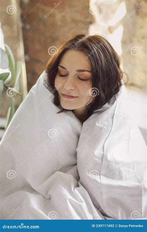 Portrait Of Young Beautiful Happy Woman Sitting Wrapped In Duvet With