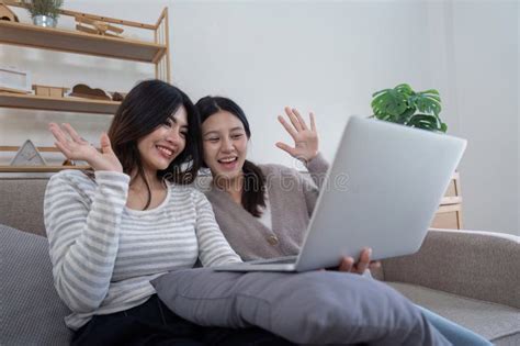 Lesbian Couple Enjoying A Video Call Together On A Cozy Sofa In A Modern Living Room Stock Image