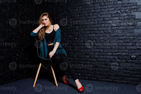 Handsome Brunette Girl Wear On Black And Green Jacket In Red High Heels Sitting And Posing On