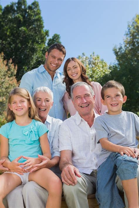 Familia Multi Alegre De La Generación Que Se Sienta En Un Banco En